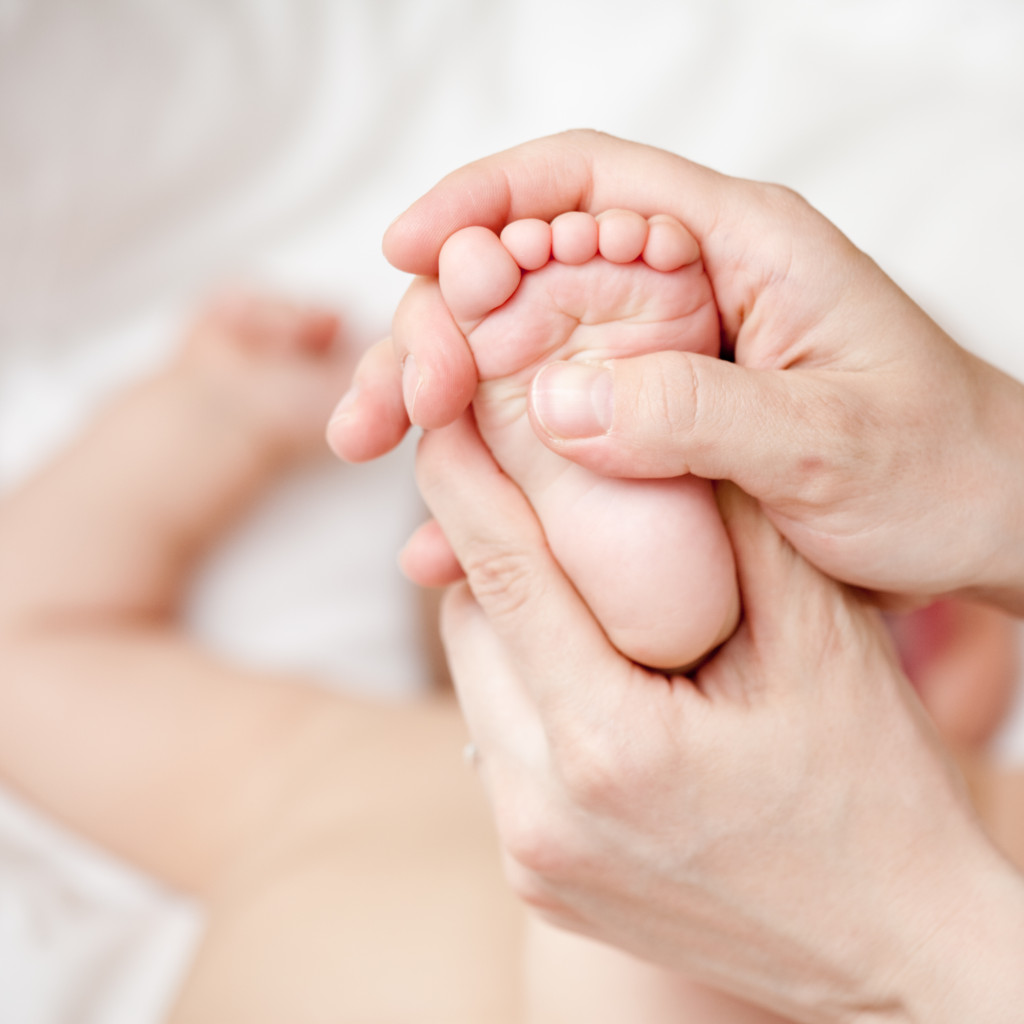 Mother massaging her child's foot shallow focus