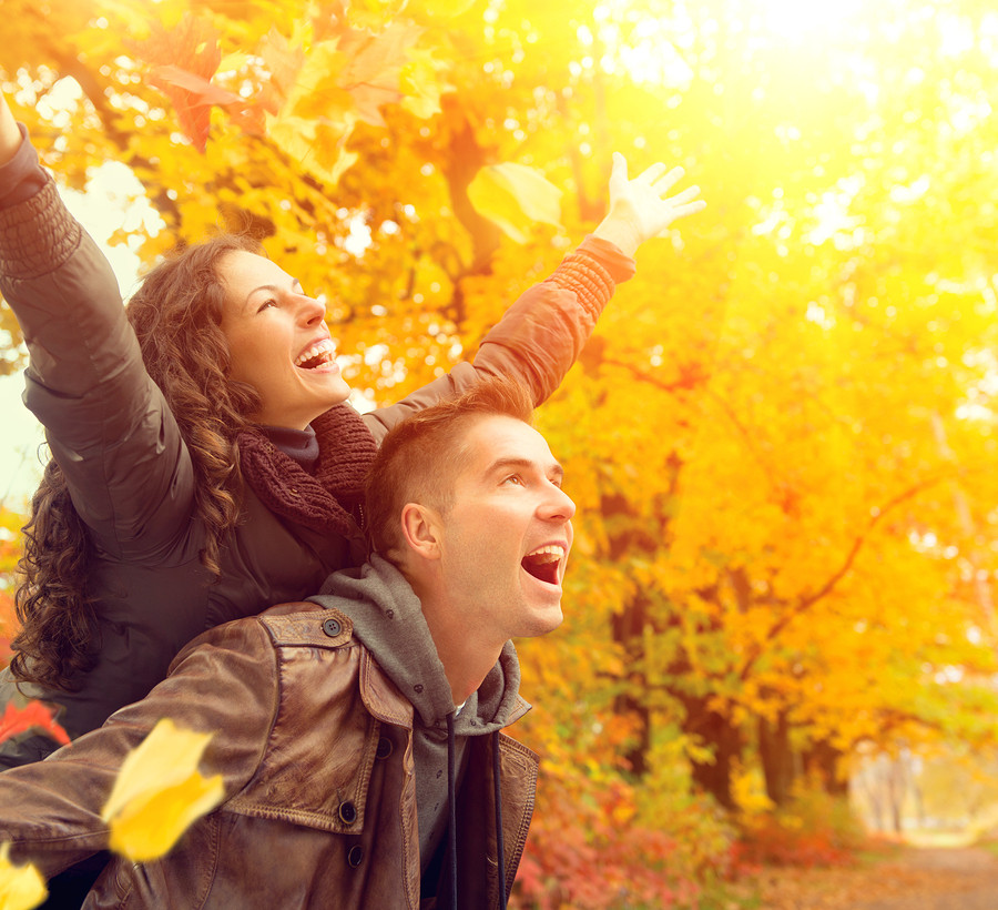 Happy Couple in Autumn Park. Fall. Young Family Having Fun Outdoors. Yellow Trees and Leaves. Laughing Man and Woman outside. Freedom Concept.