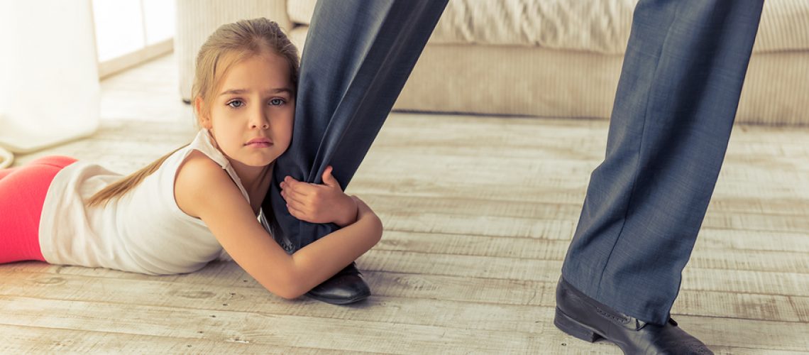Cropped image of cute little girl looking at camera while hugging her father's leg not letting him go