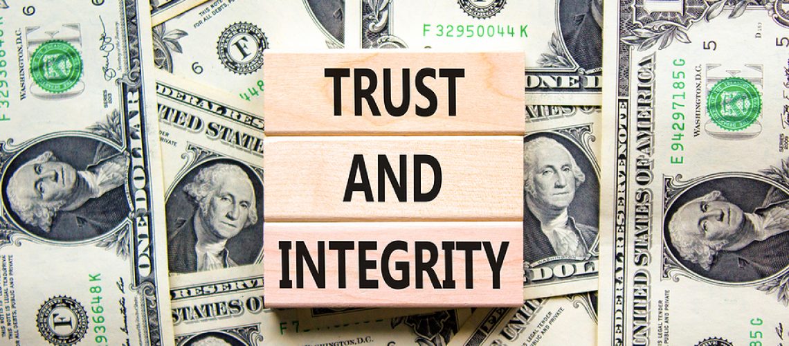 Trust and integrity symbol. Concept words Trust and integrity on wooden blocks. Dollar bills. Beautiful background from dollar bills. Business, psychological trust and integrity concept. Copy space.