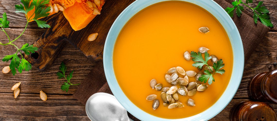 Pumpkin soup. Vegetarian soup with pumpkin seeds in bowl on wooden table, top view